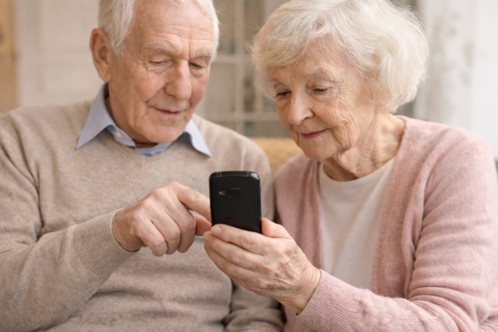 Starsze małżeństwo trzyma prosty telefon komórkowy z dużymi przyciskami, przeznaczony dla seniorów.